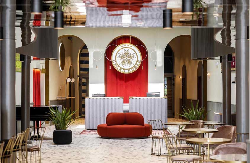 mesas, cadeiras, sofá e planta em restaurante de hotel grand koper na eslovenia