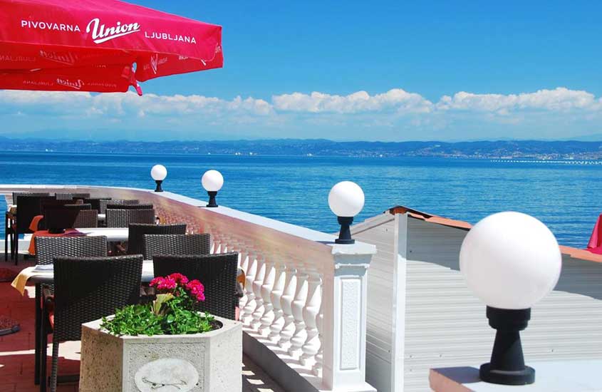 cadeiras e mesas em varanda com vista para o mar de hotel fiesa em piran, na eslovênia, durante o dia