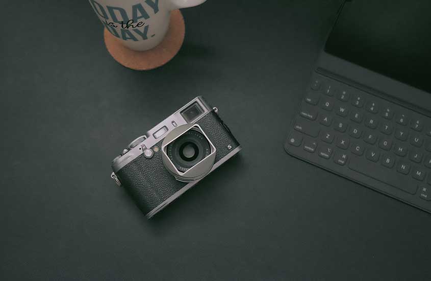 câmera fotográfica e notebook em cima de mesa preta
