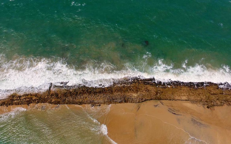 vista aérea de mar e areia, durante um dia ensolarado em uma das praias de pipa rn