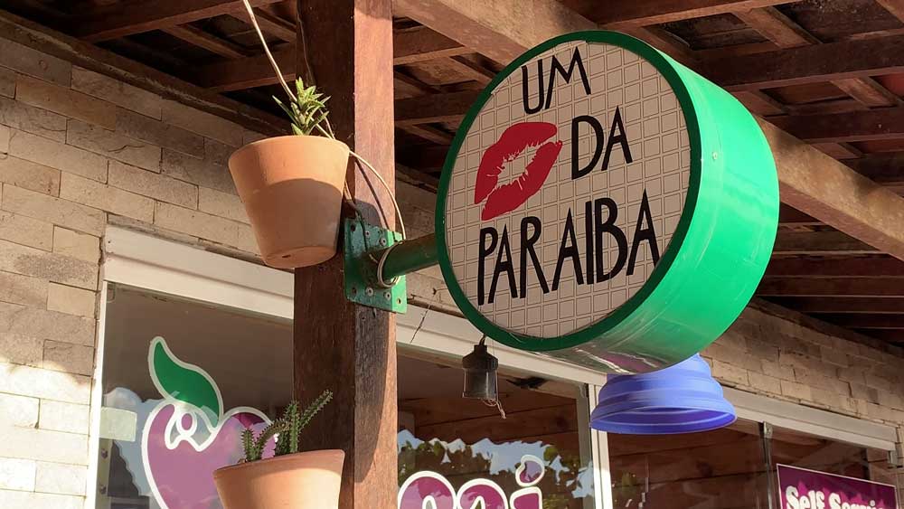 fachada e um comércio em João Pessoa, onde há uma placa escrito ''um beijo da paraíba''