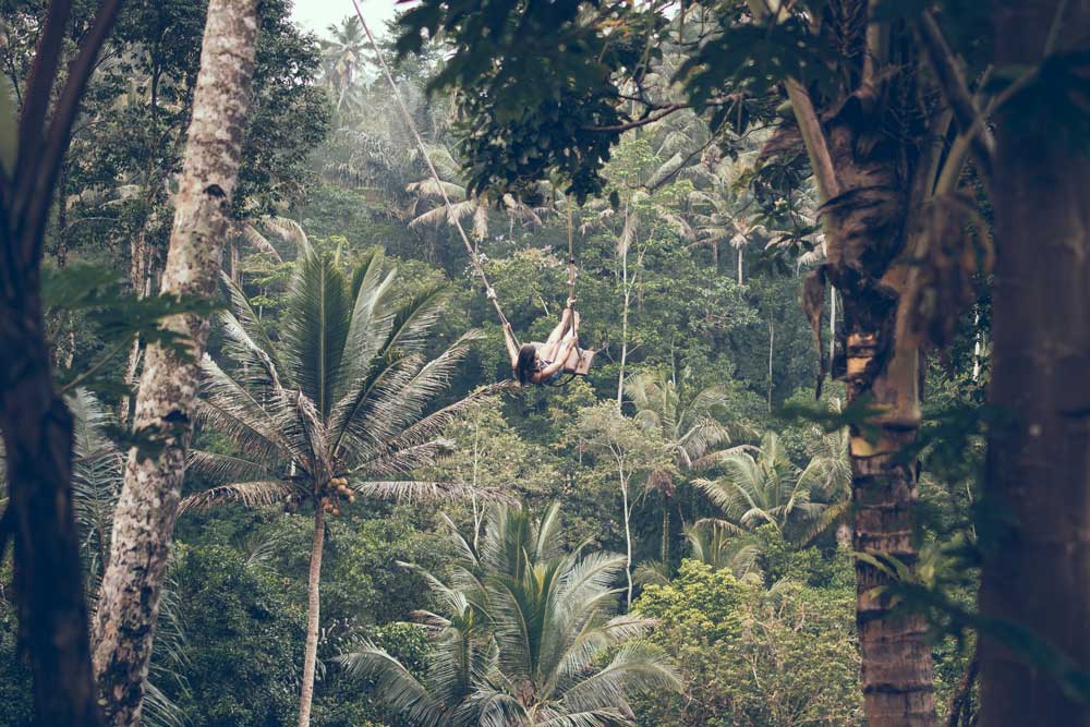 viajante balança em balanço pendurado em árvores. Para quem busca o que fazer na ilha de bali, essa é uma opção divertida