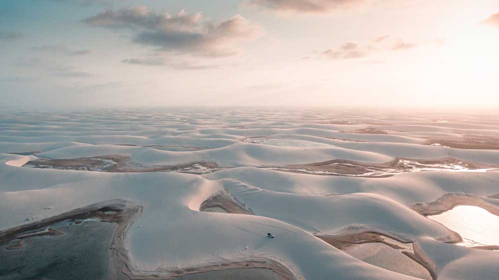 Vista área de dunas brancas, durante o dia, em Lençóis Maranhenses, um dos lugares para viajar a dois