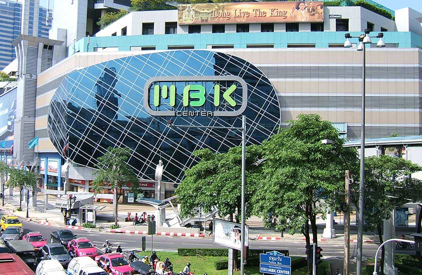 Carros circulam em estrada, durante o dia, ao lado de Mbk Center, um grande shopping center em Bangkok