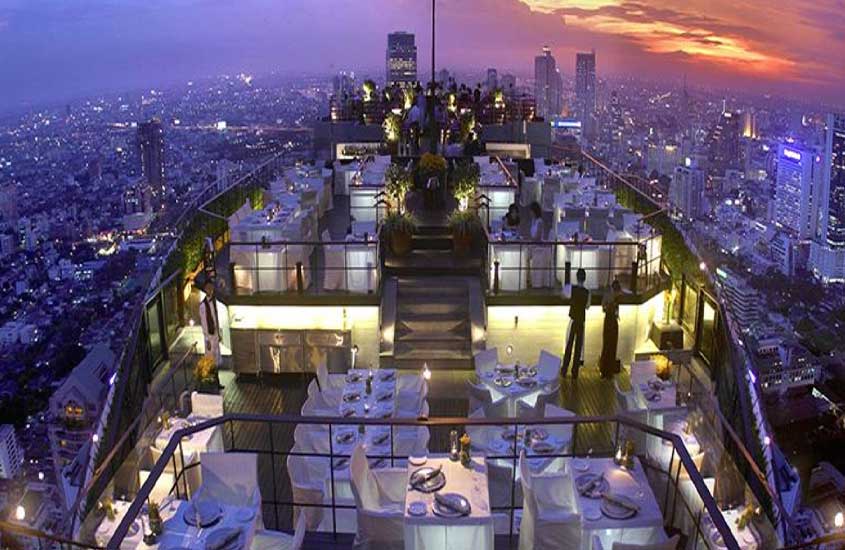 durante entardecer, vista aérea de mesas e cadeiras brancas em cobertura de hotel em Bangkok