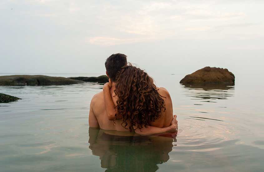 Casal se abraçando dentro do mar durante o dia