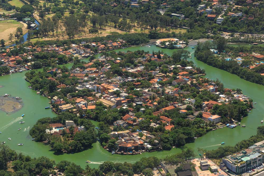 Vista aérea de barcos em lagoa, árvores e construções de Ilha da Gigóia, localizada na Barra da Tijuca, onde há boas opções de passeios do rj
