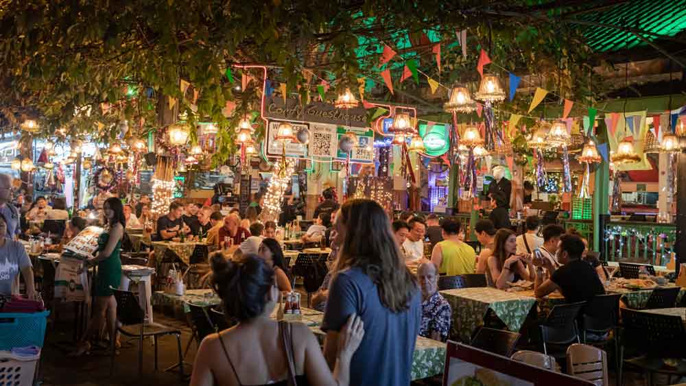 durante a noite, pessoas convernsando, comendo e bebendo em um dos restaurantes em Bangkok