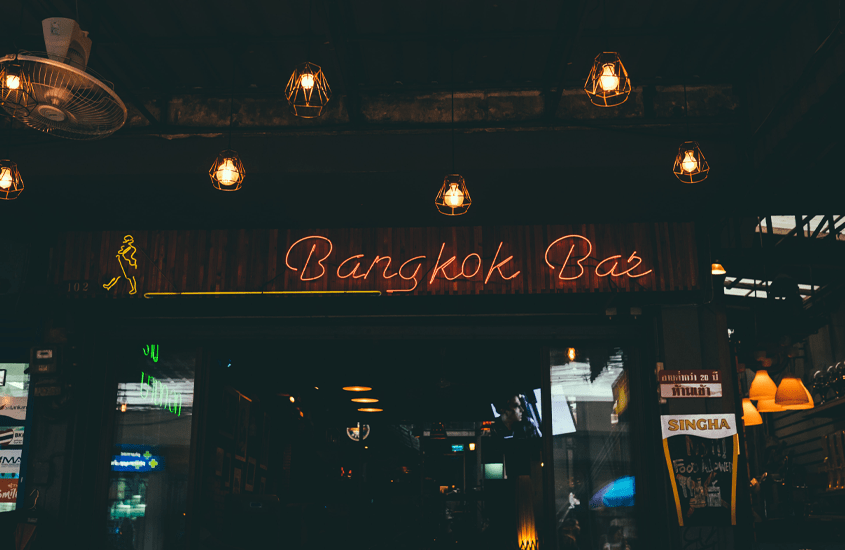 durante a noite, letreiro vermelho iluminado escrito 'bangkok bar'