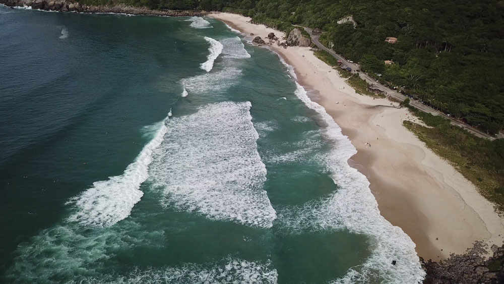 Vista área do mar, areia e vegetação de Prainha, praia do Rio de Janeiro.