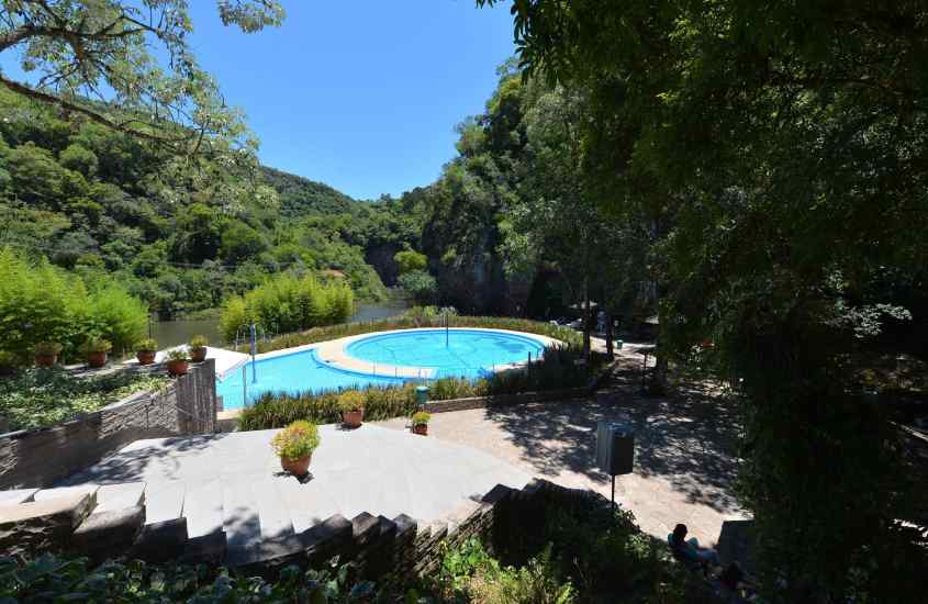 Em um dia ensolarado, piscinas de água termal com árvores e plantas ao redor