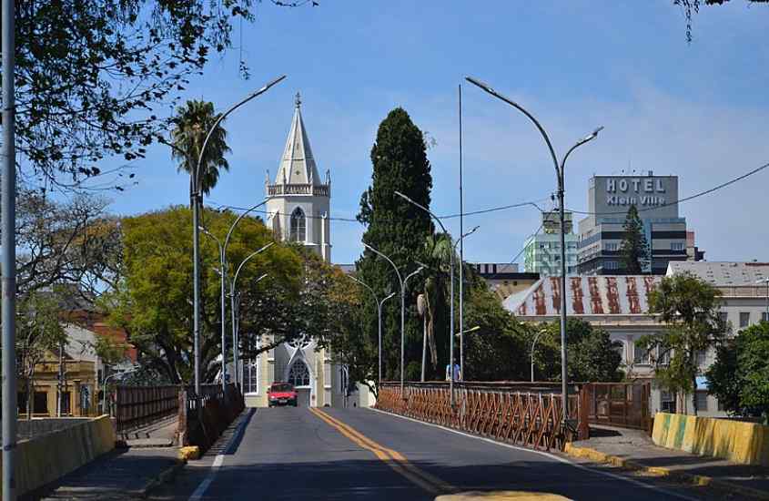 Em um dia de sol, centro de São Leopoldo com contruções, igreja e árvores ao redor