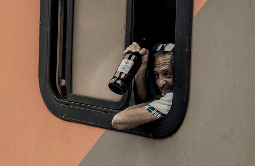 homem em ônibus, segura garrafa de cerveja. Uma das curiosidades da África do Sul é que não é tão fácil assim comprar bebidas alcoólicas