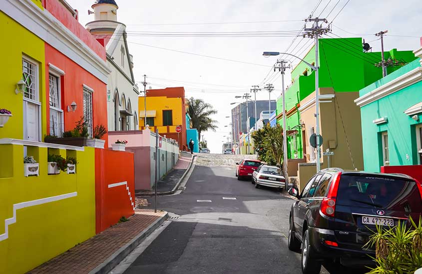 casas coloridas e carros em rua de África do Sul