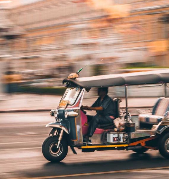 durante o dia, homem dirige tuk tuk em Bangkok