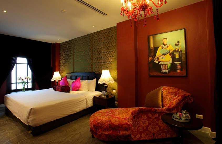 cama de casal e sofá em quarto de Shanghai Mansion, um dos melhores hoteis em bangkok tailandia