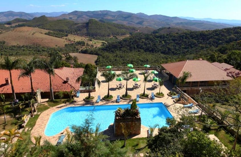 durante o dia, vista aérea de piscina cercada por árvores, com vista para as montanhas em área de lazer de Hotel Alpha Ville Chalés