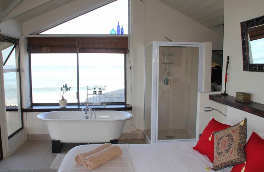 banheira e cama de casal em quarto de Beach Music, hotel da África do Sul
