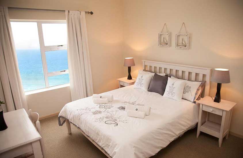 cama de casal e mesa em quarto de Diaz Beach Apartment em Diaz, uma das melhores praias da África do Sul