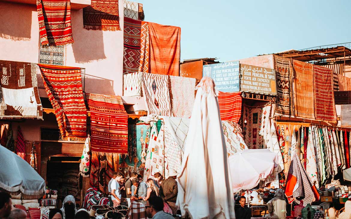 pessoas olhando tecidos coloridos expostos para venda, durante o dia, no marrocos