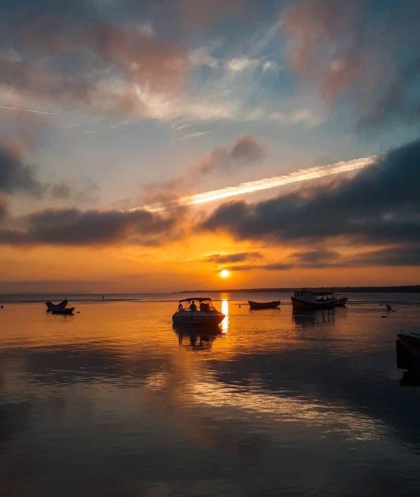 barcos em mar durante o pôr do sol em Ilha do Mel, um dos destinos baratos no brasil