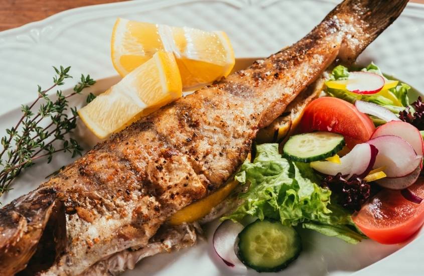 peixe assado, tomate, pepino e alface em prato branco