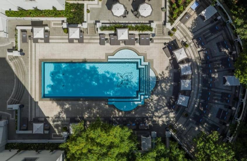 vista aérea de área de lazer de palácio tangará, um dos hotéis de luxo no brasil, onde há piscina e guarda-sóis em dia ensolarado