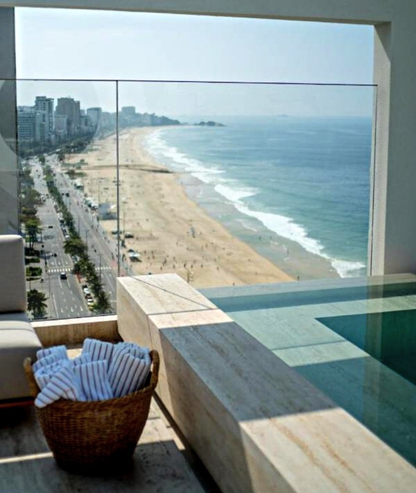 toalhas de banho dentro de cesto em chão de varanda com vista para a praia, durante o dia, em janeiro hotel, um dos melhores hotéis de luxo no brasil