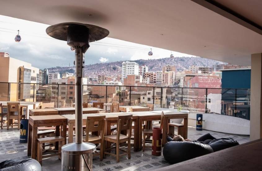 cadeiras e mesas em terraço de the adventure brew hostel, com vista para prédios, na bolívia