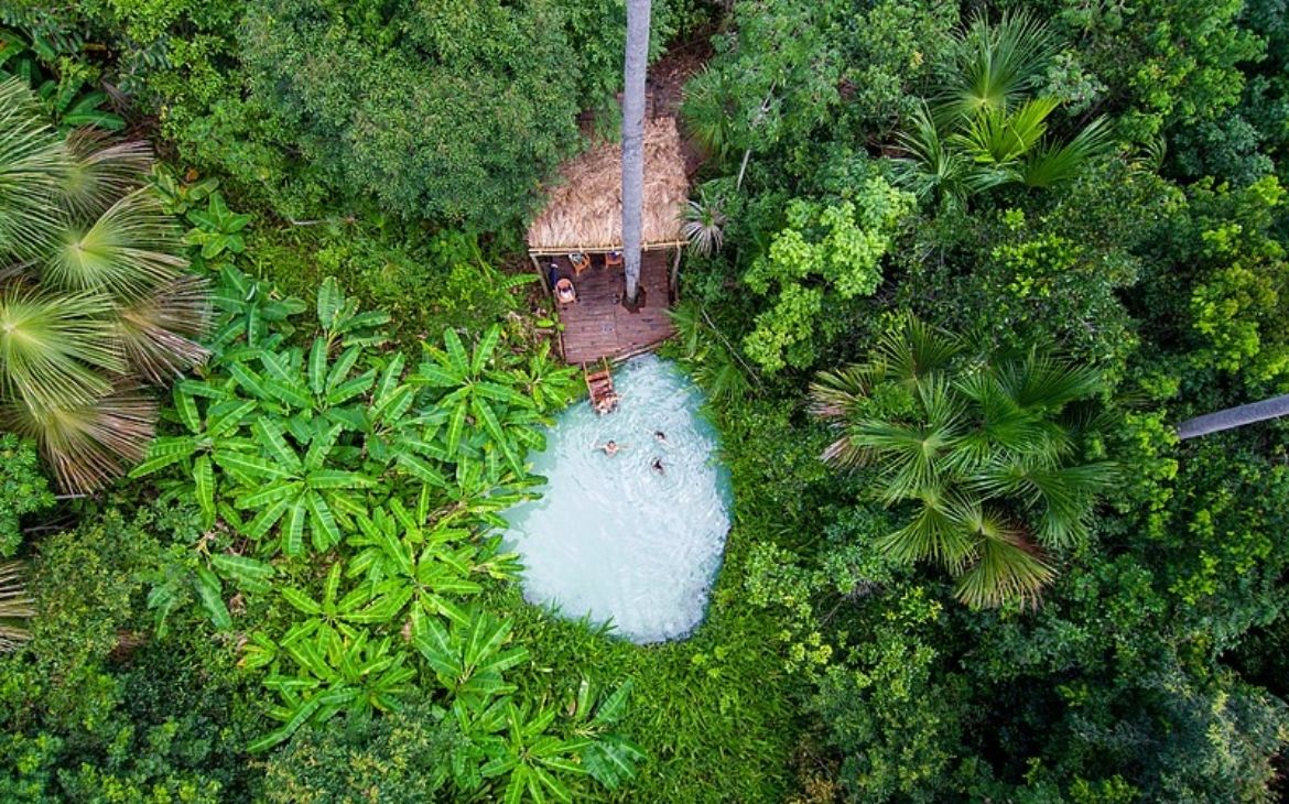 vista aérea de pessoas tomando banho em fervedouro cercado de árvores no jalapão