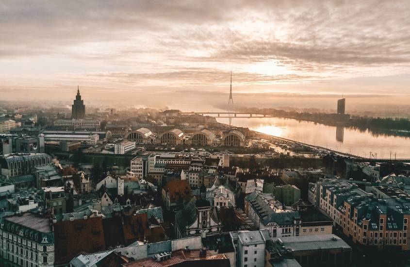 vista aérea de casas, prédios e rio, durante o entardecer em letônia, um dos países mais baratos para viajar na europa