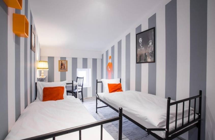 duas camas de solteiro em quarto com paredes cinzas e brancas de ab hostel na polônia