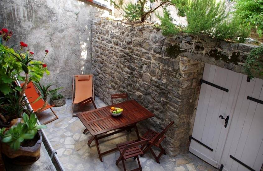 cadeiras e mesa de madeira em varanda com plantas de freedom hostel budva, acomodação em montenegro