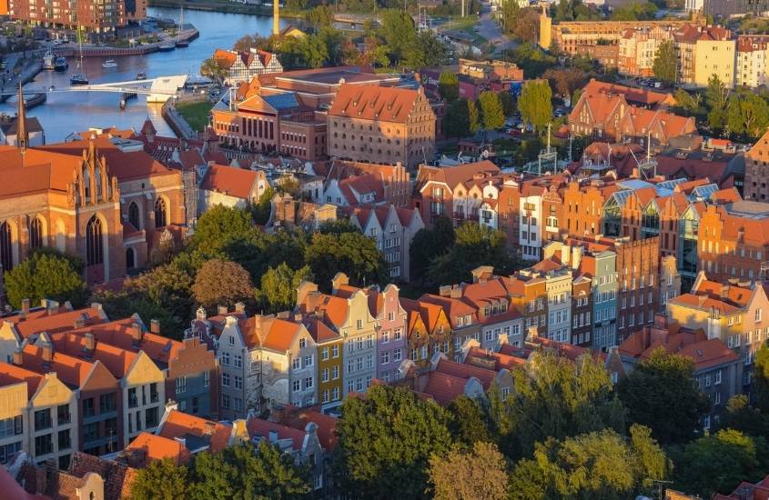 vista aérea de casas, árvores e rio, durante o dia, na polônia, um dos países mais baratos para viajar na europa