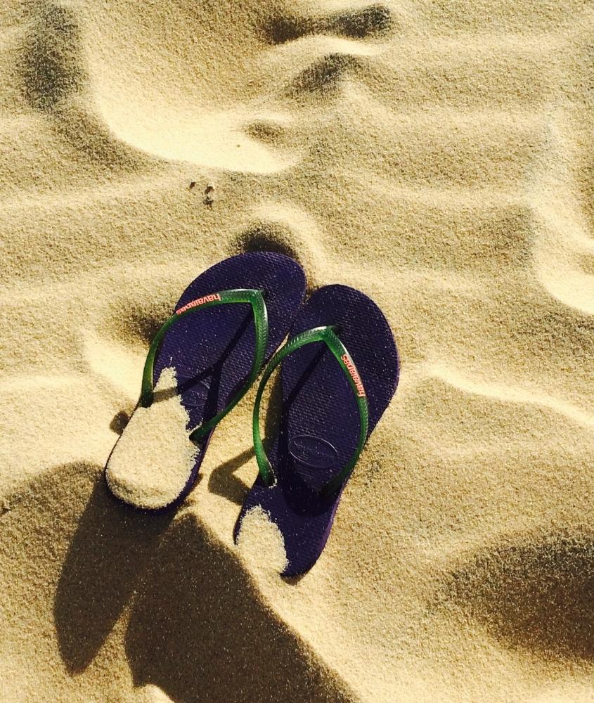 chinelo azul e verde em cima de areia de praia, durante o dia