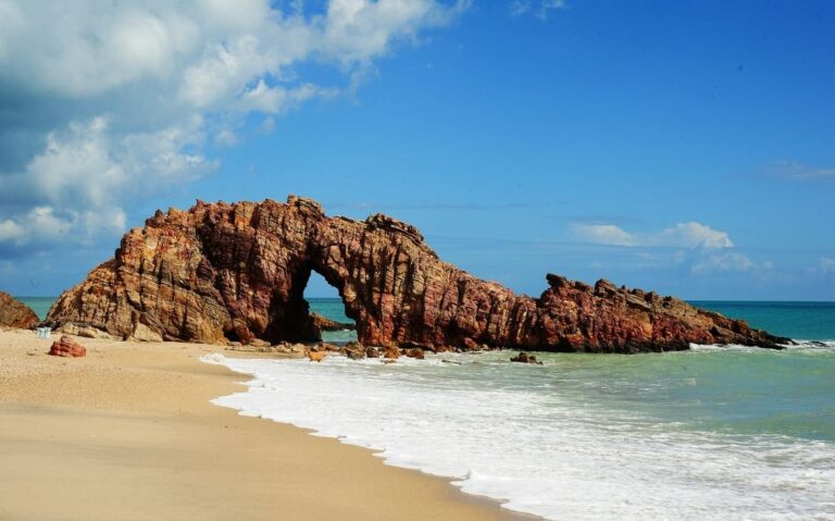 rocha furada no meio, em praia, durante o dia, em jericoacoara