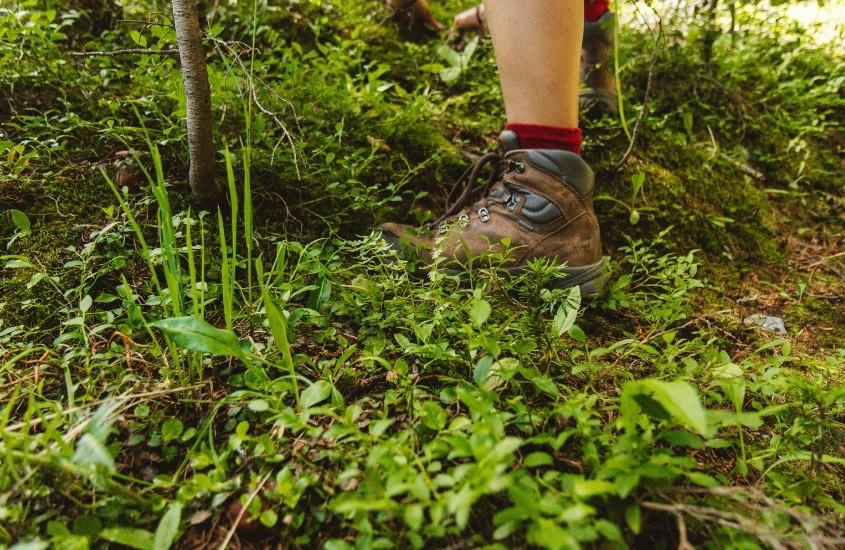 perna do tornozelo para baixo de viajante com tênis marrom, caminhando em trilha na serra do cipó