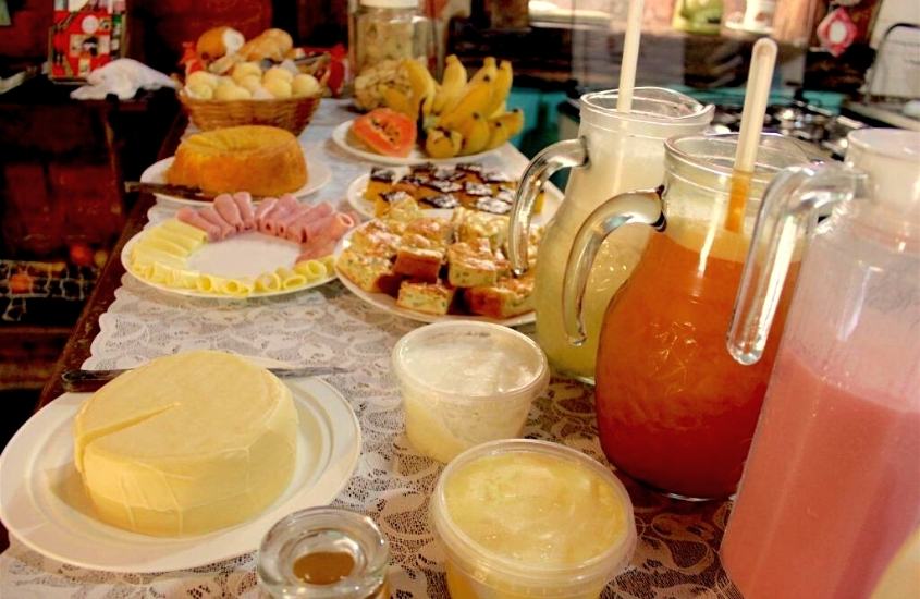 queijos, bolos, sucos em mesa de café da manhã da pousada bangalôs cipó