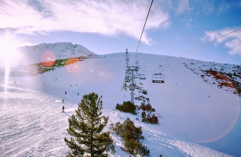 pessoas esquiam, durante o dia, em bansko, um ótimo destino para quem procura o que fazer na bulgária