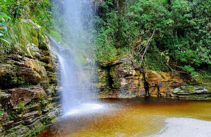 água de cachoeira caindo em rio, cercado de arvores em ibitipoca, um dos melhores lugares para relaxar em minas gerais