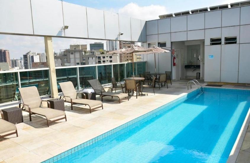 espreguiçadeiras em frente a piscina, durante o dia, em área de lazer de san diego convention lourdes, um dos melhores hotéis em belo horizonte