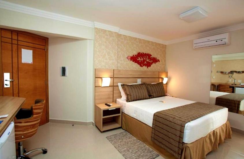 cama de casal, mesa, cadeira e frigobar em quarto de bristol jaraguá hotel pampulha