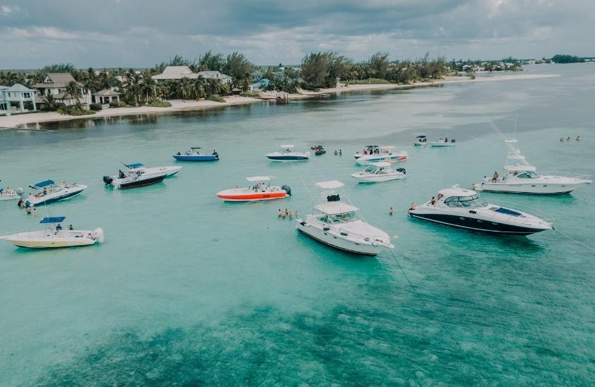 barcos em mar azul, durante o dia em de ilhas cayman, um dos lugares mais caros do mundo para viajar
