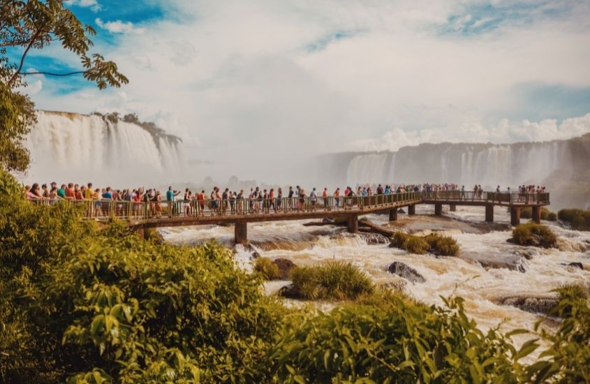 durante o dia, pessoas em passarela observando Cataratas do Iguaçu, uma boa atração para quem está buscando o que fazer em foz do iguaçu em 3 dias