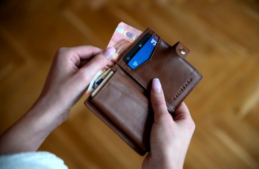 mulher segurando carteira com cartão e dinheiro