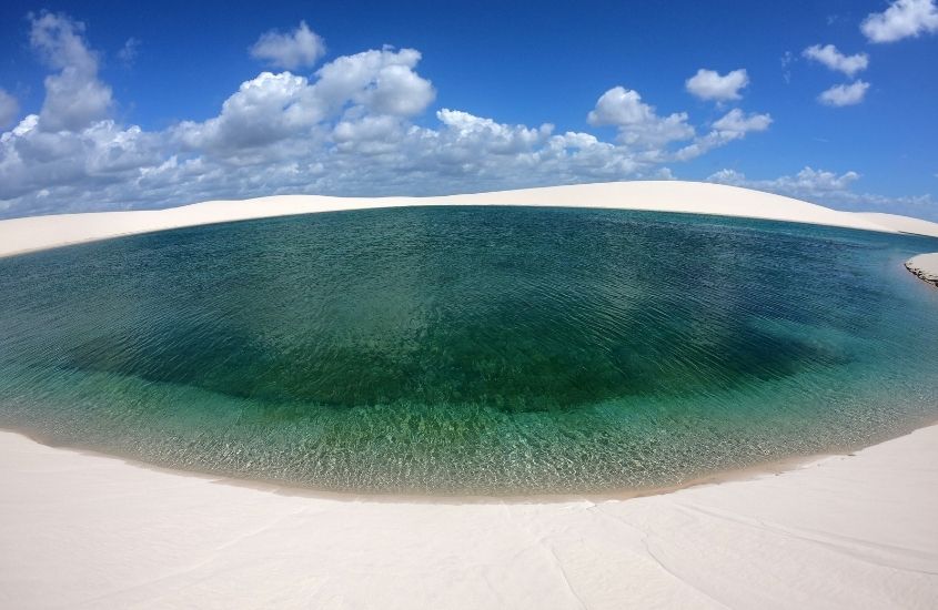 lagoa cercada por areia, durante o dia, nos lençois maranhenses