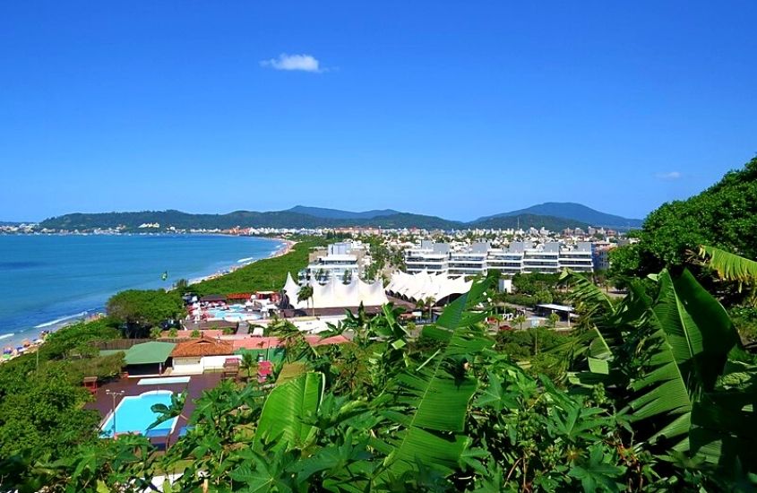 vista aérea de casas e árvores em frente a praia, durante o dia em Jurerê, uma ótima área onde ficar em Florianópolis