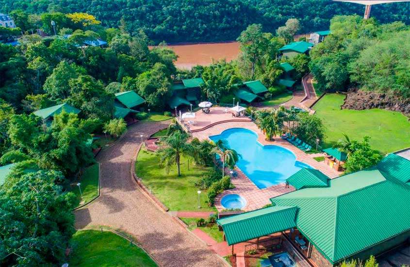 Vista aérea de hotel em foz do iguaçu perto das cataratas com piscinas, espreguiçadeiras, parte gramada e árvores ao redor