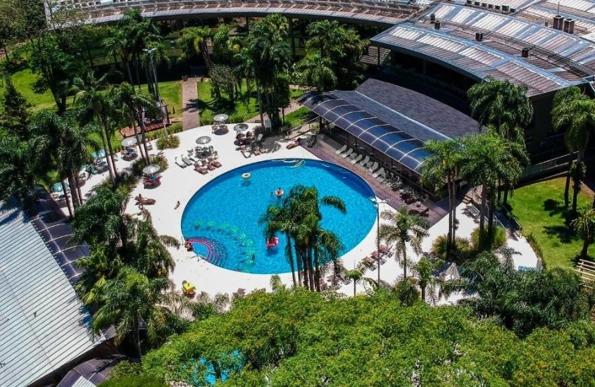 durante o dia, vista aérea de piscina cercada de árvores em área de lazer do Vivaz Cataratas Hotel Resort, um dos hotel perto das cataratas do iguaçu