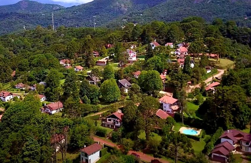vista aérea de árvores, montanhas e casas, durante o dia em monte verde um dos lugares para casal em minas gerais